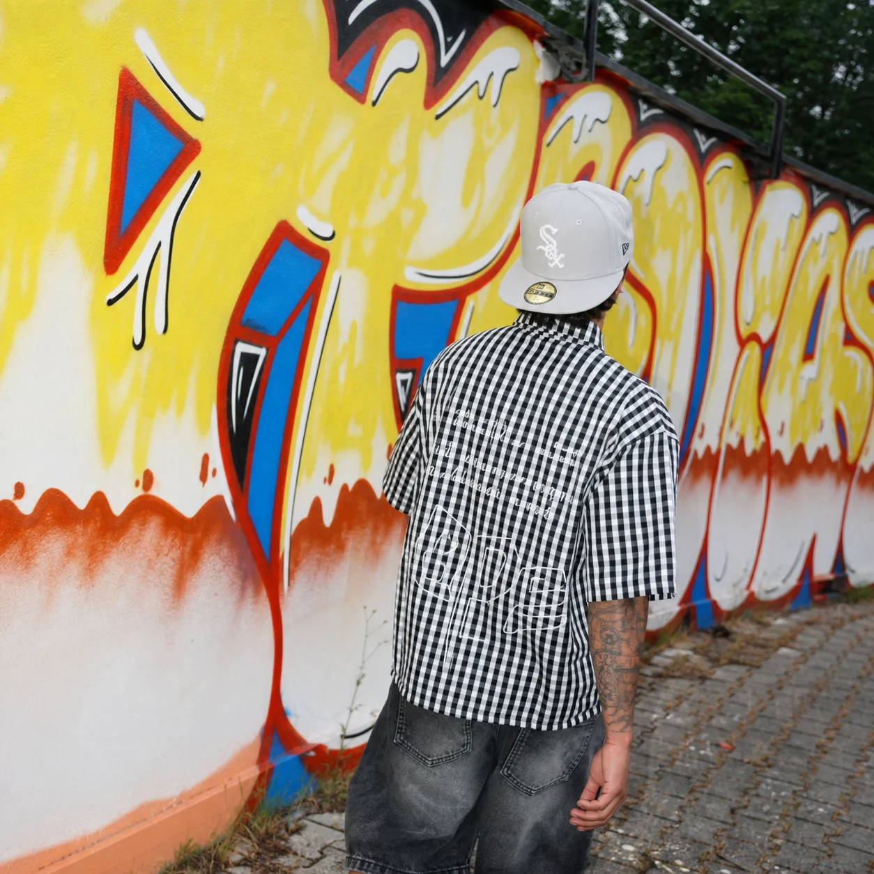 Culture23 Instagram camicia check davanti a graffiti